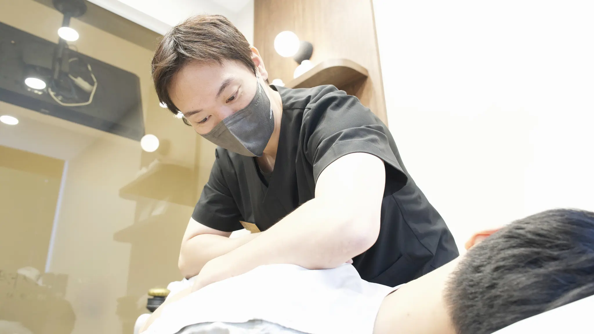 한의사가 치료 침대에 누운 환자의 등을 손으로 누르며 추나 치료를 하는 모습